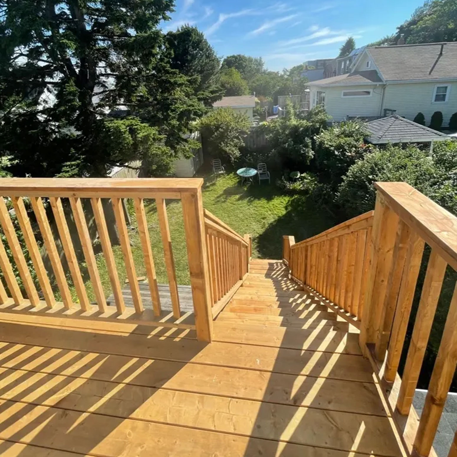 A wooden deck with a fence and backyard in the background