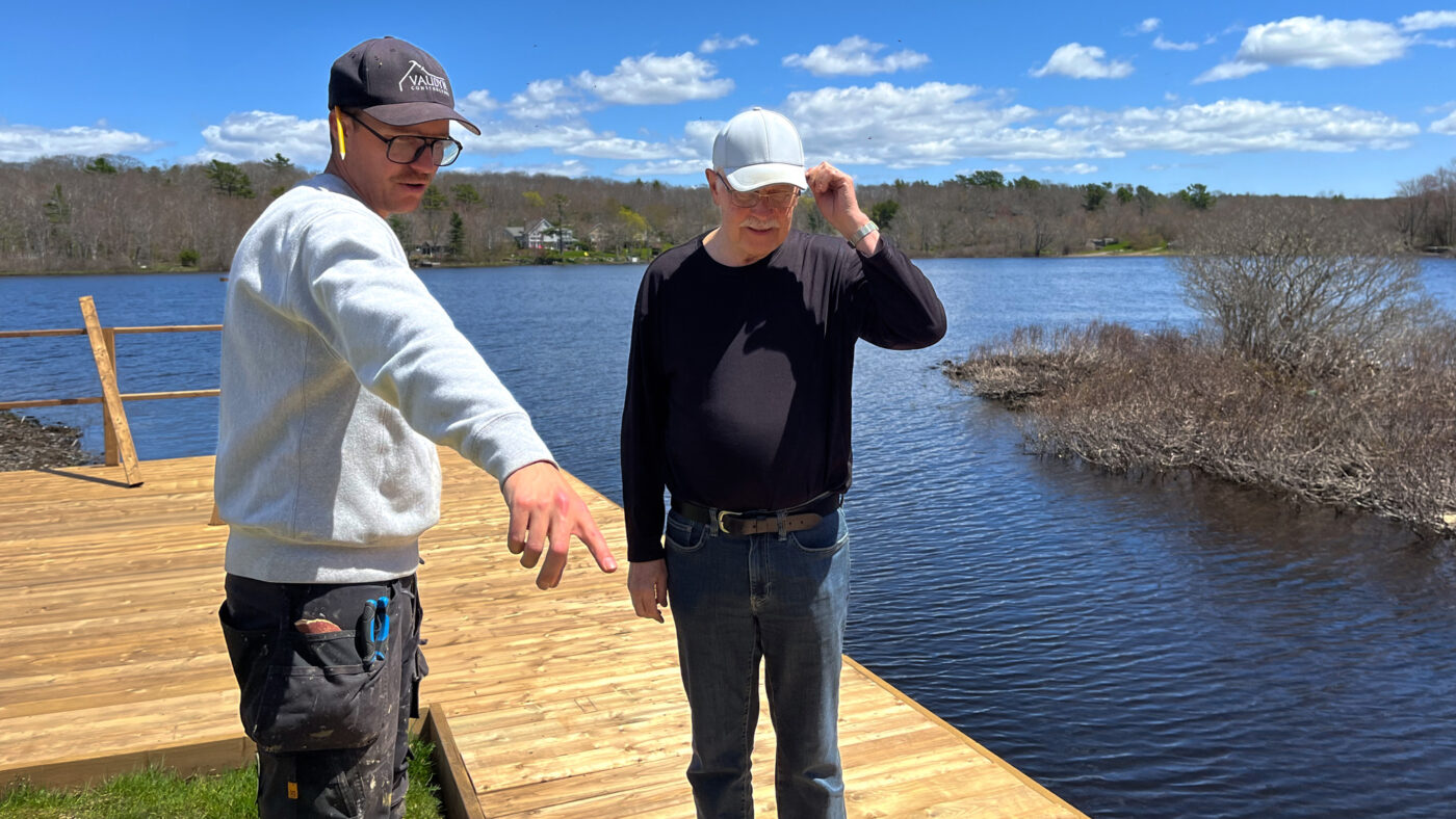 Two men standing on a deck near water